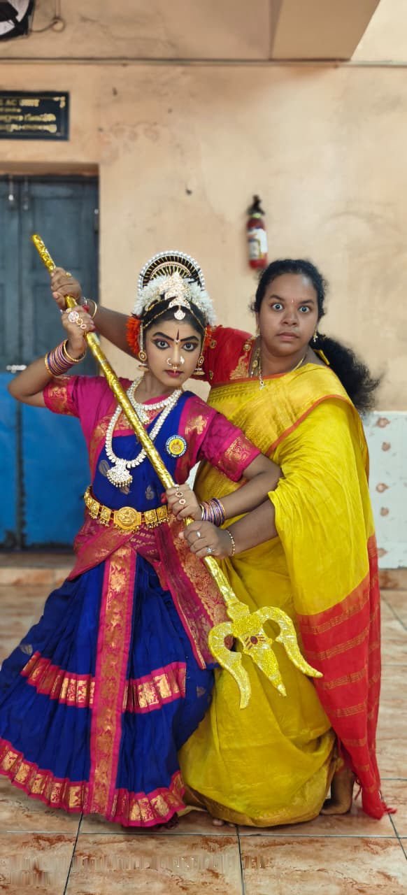 Student solo pose in green and maroon costume in classical pose