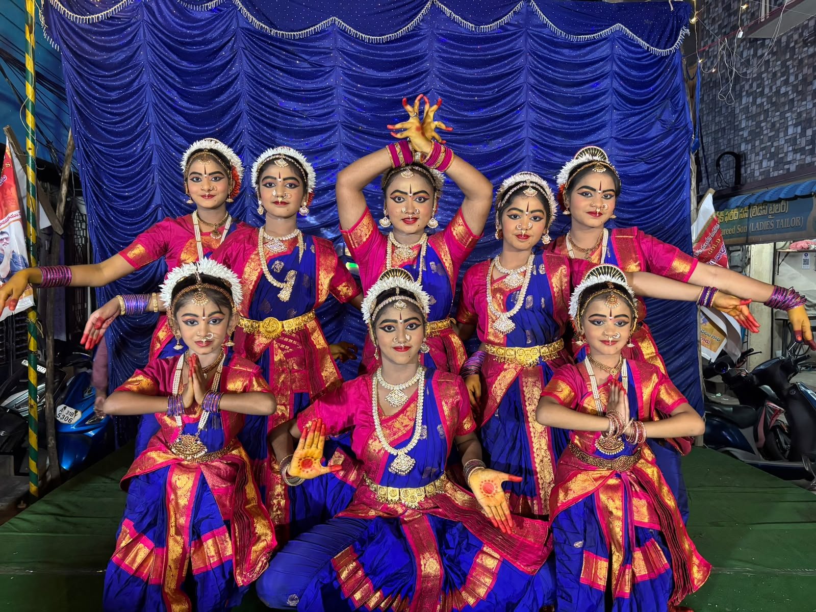 Students formation in traditional dance attire with green backdrop